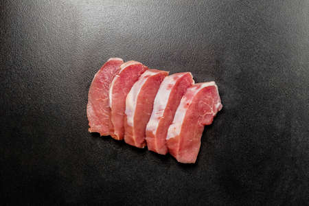 Raw meat steaks on black textured background Pieces of fresh boneless pork, meat steaks. Piece of red raw meat on a dark backgroundの写真素材