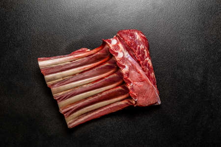 Fresh raw beef spare ribs. Uncooked mutton rack of beef. Piece of meat with bones on black ceramicの写真素材