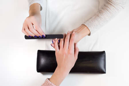 Top view manicurist at work nail file hand little finger of client.Hand on the black professional pillow.の写真素材