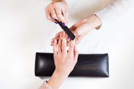 Top view of image of hands polishing fingers on towel clients central finger. Woman in nail salon receiving manicure by beautician.の写真素材