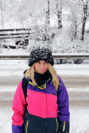 Portrait of beautiful girl in a pink color ski jacket standing on the background of a winter forest....