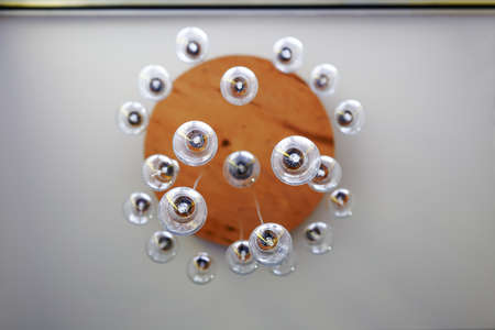 Lot of bulbs on background of the wooden circle, that are hanging at different levels, symbolizing the subordination of the companyの写真素材