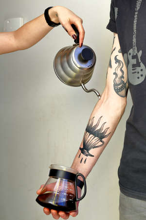 15-02-2016, Kiev, Ukraine, Pour over coffee brewing method process by barista with tattoos in natural light an wooden backgroundのeditorial素材