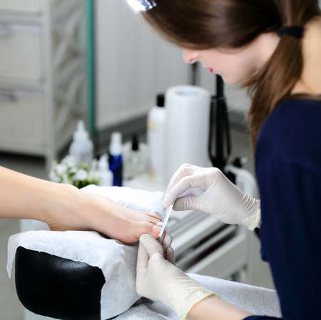 Master chiropody doing pedicure in salon on the background of the equipment for a pedicureの写真素材