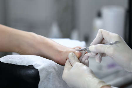 Close up shot of pedicure process, which is made in white glovesの写真素材