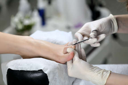 Close up Cutting cuticle on foot, nail scissors. On backgroun of flower and equipment for Pedicure processの写真素材