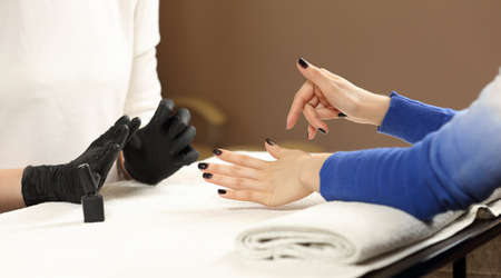 Closeup shot Finished customer manicure, clients hands and the hands the master of manicure in the process.の写真素材