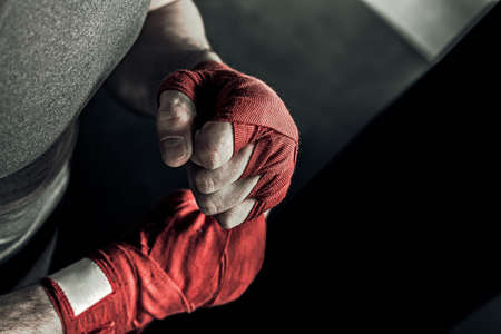 Closeup male hand of boxer with red boxing bandages. Fists of fighter before the fight or training in sport gym.の写真素材