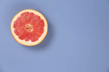 Photo kinds of pop art. Grapefruit on a blue paper texture background in the upper left cornerの写真素材