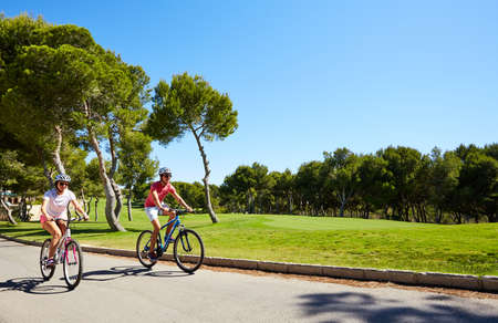 Orihuela, Spain - June 17, 2016: A pair of cyclists, boy and girl, going near beautiful golf courses on bicycles in helmetsのeditorial素材