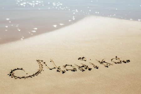 The name is written on the wet sand of the sea. The name on the sand. Against the backdrop the sea...