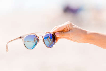 Sunglasses in hand on background of the beachの写真素材
