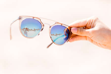 Sunglasses in hand on background of the beachの写真素材