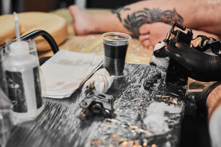Tattoo master in black gloves, tattoo on the skin of black ink tattoo of his client in the salon.の写真素材
