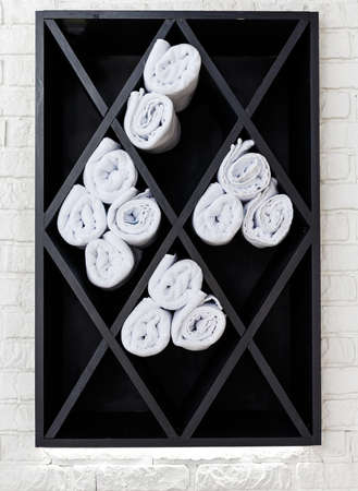 Black cabinet with white towels, which are twisted into a rollの写真素材