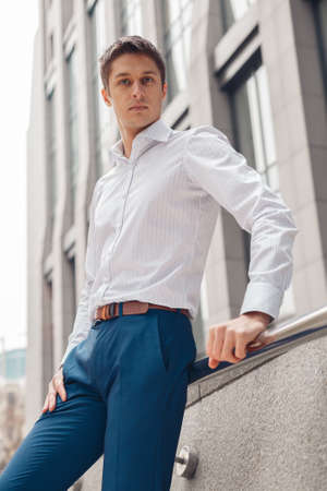 Young man dressed formal resting outdoors near business center. Serious young man in city.の写真素材