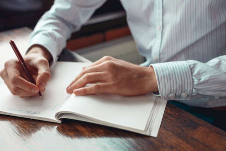 Concept To do list message on notebook with businessman hands, pen and coffee cup on wooden table.の写真素材