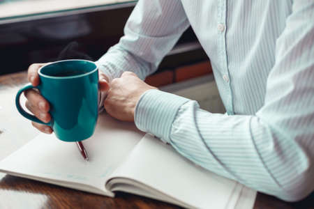 Close up businessman hands with cup of coffee. Coffee break in cafe.の写真素材
