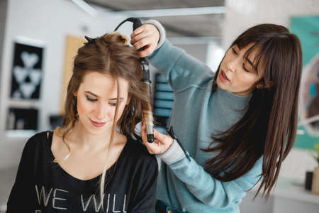 Kyiv, Ukraine - March 3, 2017: Closeup hairdresser coiffeur makes hairstyle. Female hairstyles on curling in a beauty salon.のeditorial素材