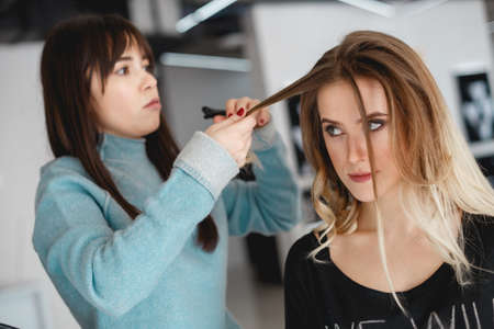 Kyiv, Ukraine - March 3, 2017: Professional hairdresser, stylist making curls in white make up room. Beauty and haircare conceptのeditorial素材