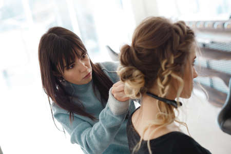 Kyiv, Ukraine - March 3, 2017: Closeup hairdresser coiffeur makes hairstyle. Beautiful woman with hairstylist in salon.のeditorial素材