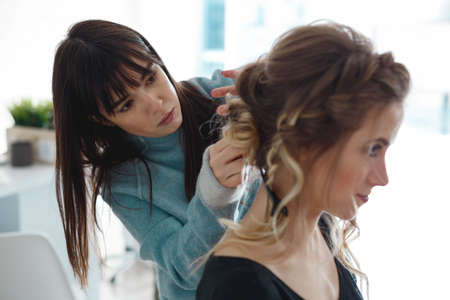 Kyiv, Ukraine - March 3, 2017: Beautiful brown hair girl visit hairdressing salon and making evening curly hairstyle. Beautiful woman with hairstylist in salon.のeditorial素材