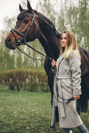 Beautiful girl communicates with the horse in the park. Preparing for the ridingの写真素材