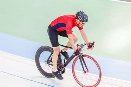 Active man on white velodrome outdoor. Sports man in a red T-shirt and a black bicycle.の写真素材