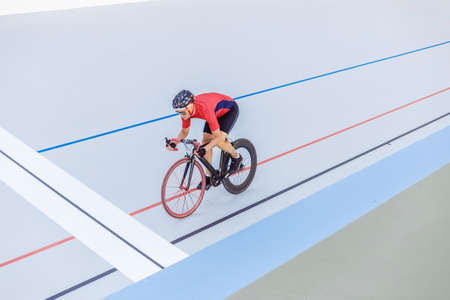 Cyclist finishes on velodrome. Professional athlete in a red T-shirt and a black bicycle.の写真素材