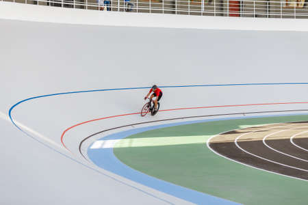 Young professional cyclist on a velodrome. Sports man in a red T-shirt and a black bicycle.の写真素材