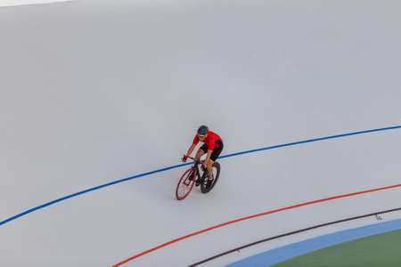 Young professional cyclist on a velodrome. Sports man in a red T-shirt and a black bicycle.の写真素材