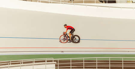 Bicyclist on cycle track outdoor. Active man racing at white velodrome.の写真素材