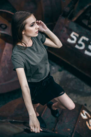Fashion portrait of stylish girl in rock black style standing outdoors against the rusty urban in the city.の写真素材