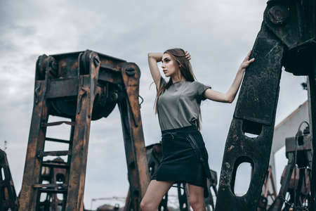 Close-up fashion woman portrait of young pretty trendy girl posing on a rusty pile of metal. Summer street style fashion.の写真素材
