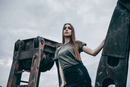 Fashion lonely girl in motion posing on city of urban background. Dressed in a black shirt and dark green t-shirt.の写真素材