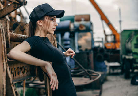 Profile of young beautiful brunette woman standing in urban background. Girl wearing casual clothes and cap.の写真素材