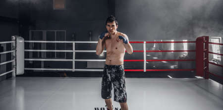 Young man boxing workout on the ring. Muscular professional kick boxer stand in the center.の写真素材