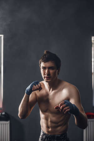 Sportsman muay thai boxer fighting in boxing hall. Isolated on black background with smoke. Copy Spaceの写真素材