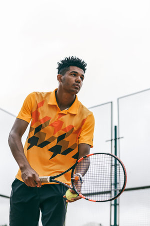 Young tennis player with racket ready to serve a tennis ball. Professional tennis player starting...