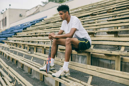 Picture of handsome young man on a bench. Man relaxing after tennis play. Man sitting on bench.の写真素材