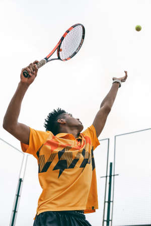 Preparing to his best serve. Full length of man playing tennis on tennis courtの写真素材