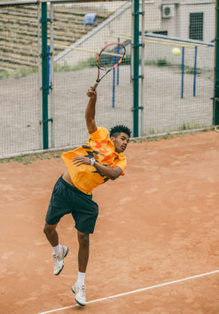 A young man beats off a ball with a tennis racket. A tennis player holds a duel on a tennis court.の写真素材