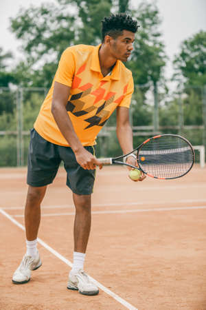 Young tennis player with racket ready to serve a tennis ball. Professional tennis player starting set.の写真素材