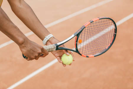 Close-up of male hand holding tennis ball and racket. Professional tennis player starting set.の写真素材