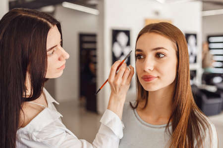Beautiful young girl got correction of eyebrows in a beauty salon. Woman correcting eyebrows formの写真素材
