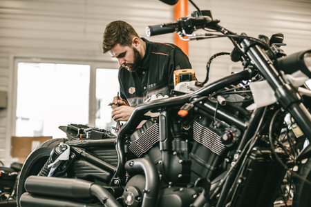Motorcycle mechanic repairing electronics sports black bike. Handsome mechanic working in auto...