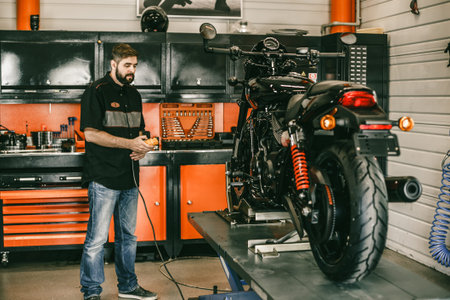 Professional moto mechanic raises a motorcycle on the lift. Man pressing up and down switch in bike...
