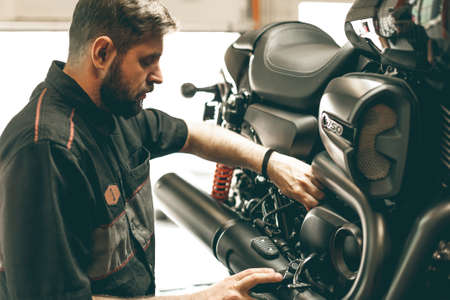 Professional bike mechanic checks the level of oil in the motorcycle. The sports bike is on the lift.の写真素材