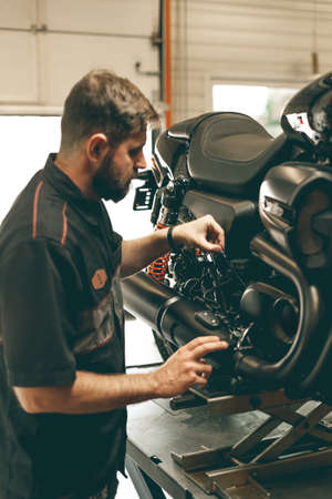 Professional bike mechanic checks the level of oil in the motorcycle. The sports bike is on the lift.の写真素材