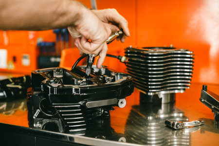 Cropped image of automobile mechanic repairing motorcycle in automobile store. Biker repairing his...
